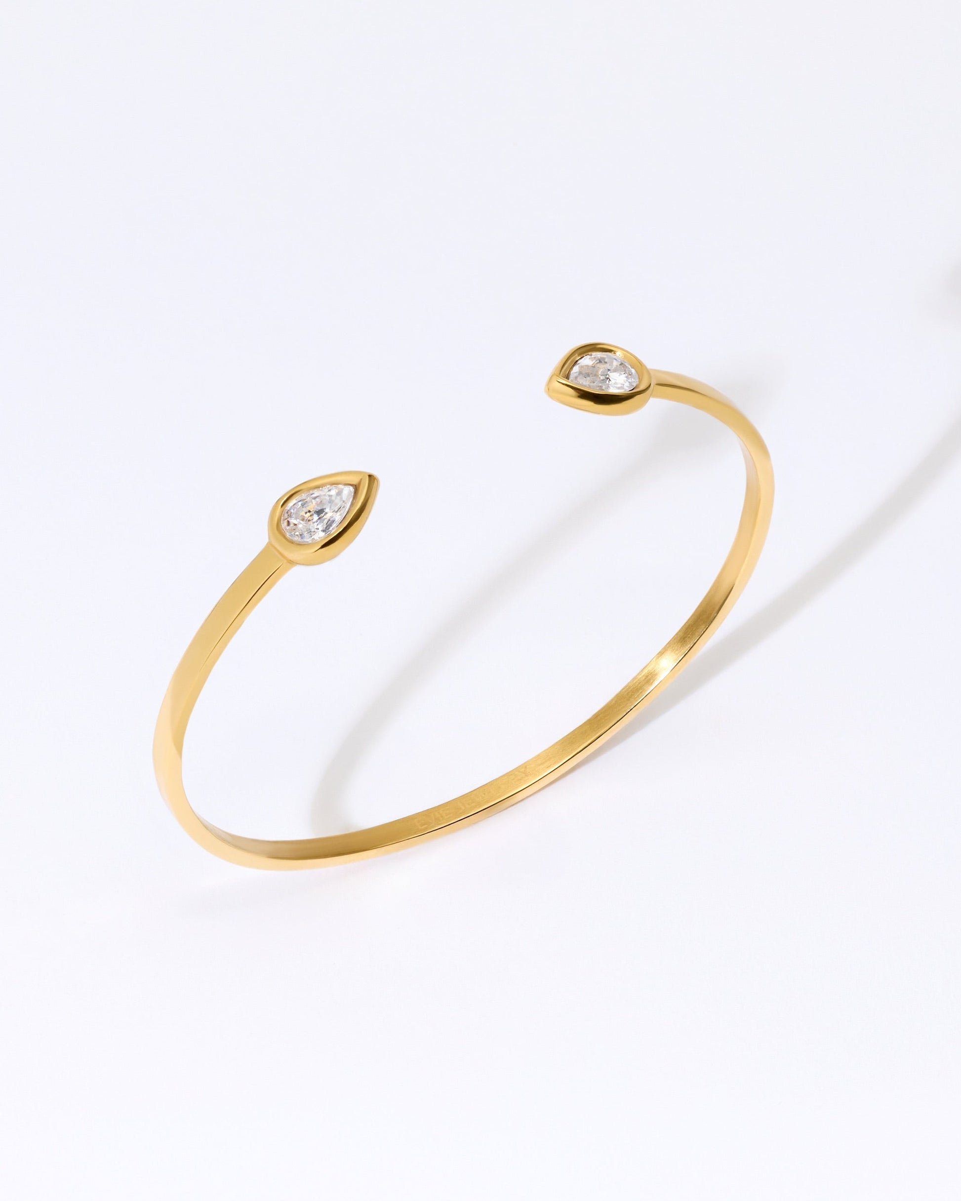 Gold bangle bracelet with two teardrop shaped crystal cz gemstones.