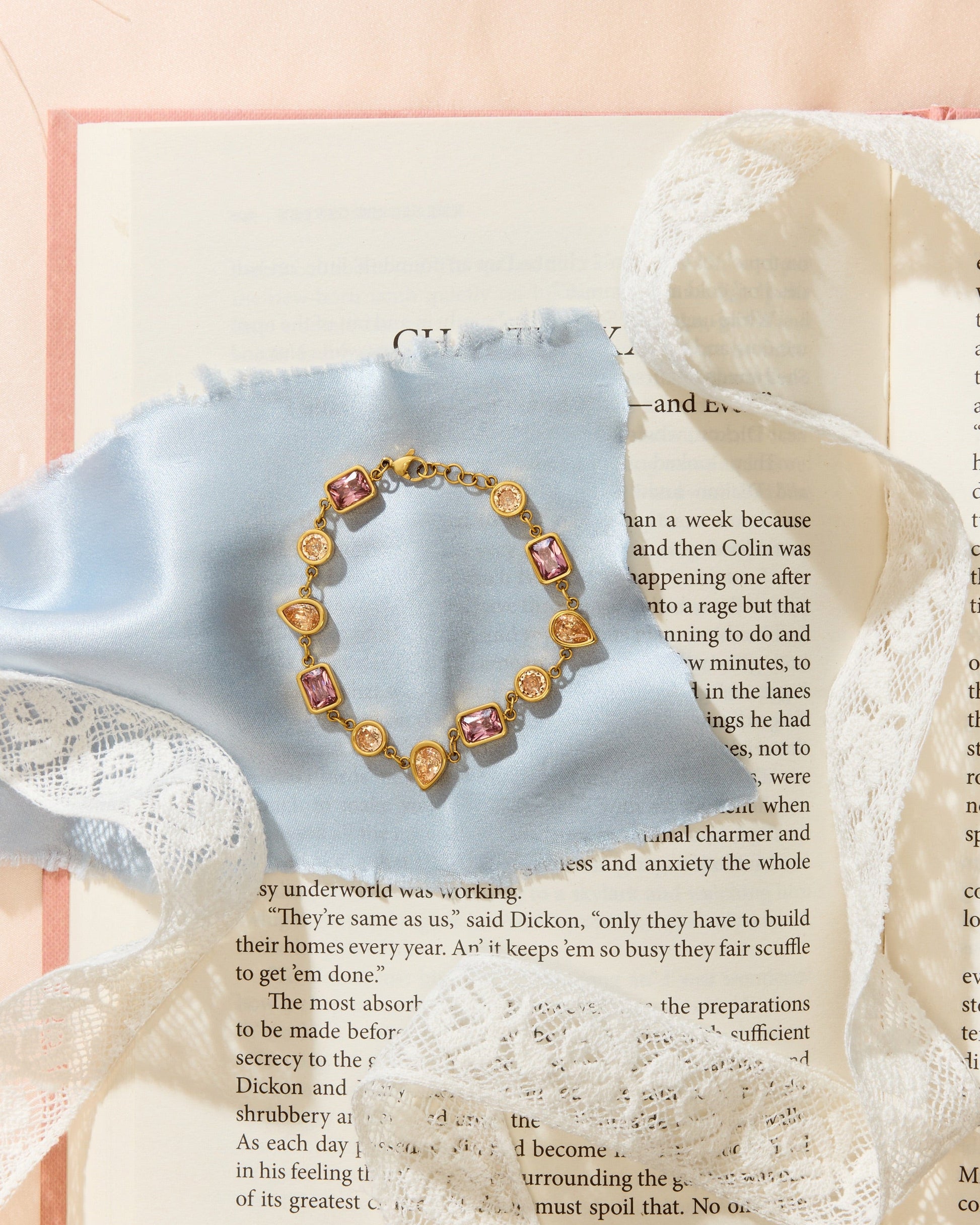 Meg Bracelet laying on an open book with blue cloth and lace.