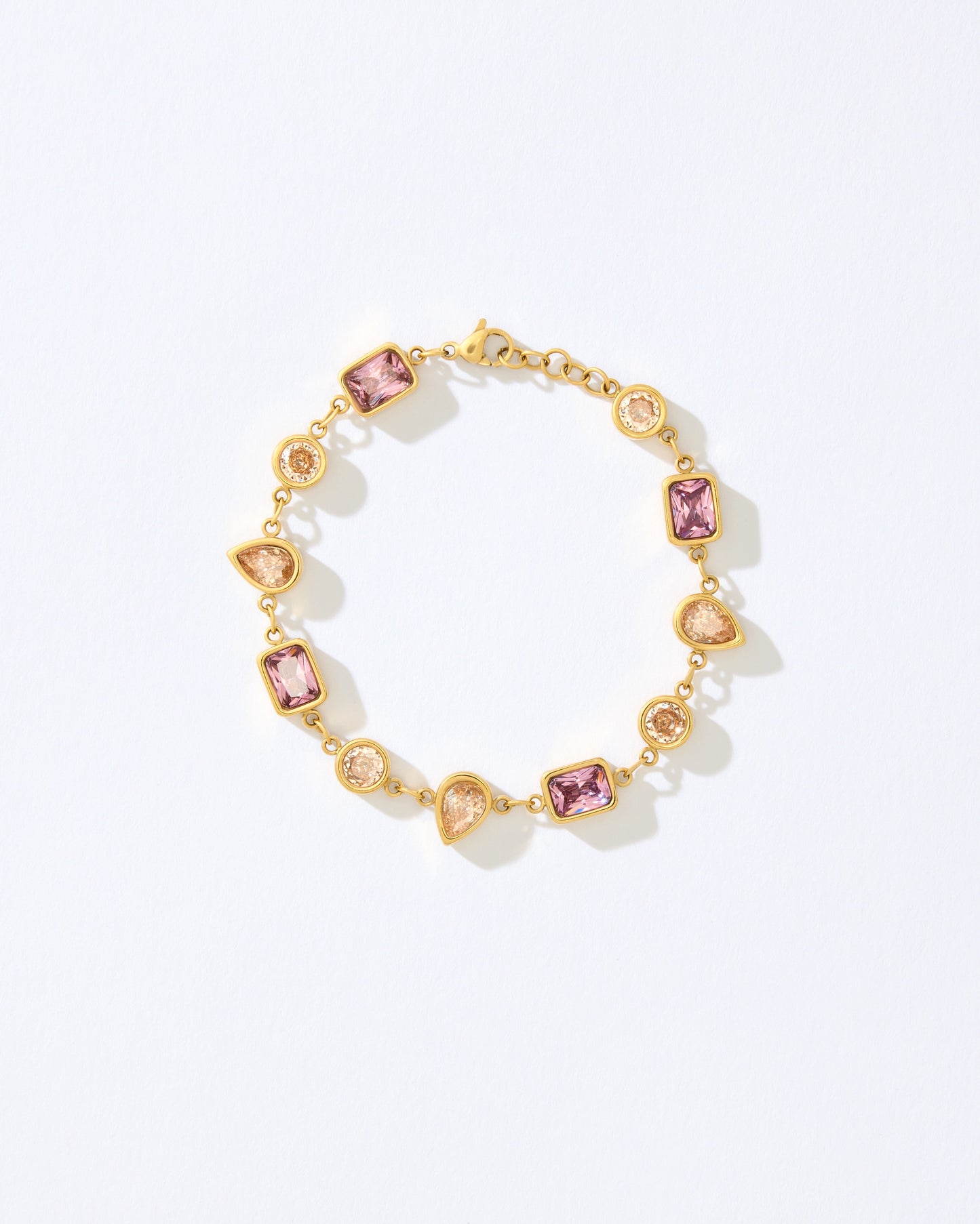 Gold bracelet with pink and orange gemstones on a white background