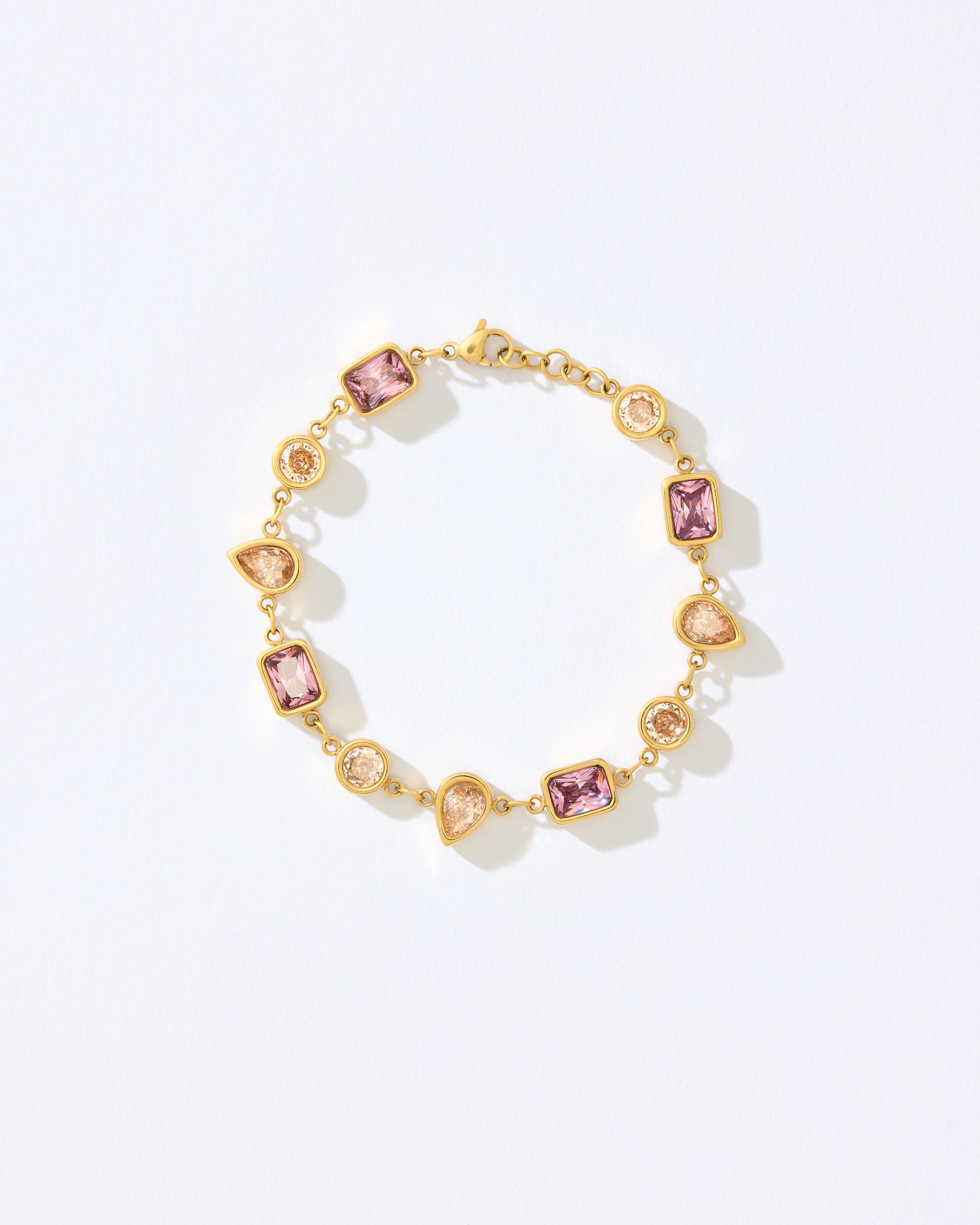 Gold bracelet with pink and orange gemstones on a white background