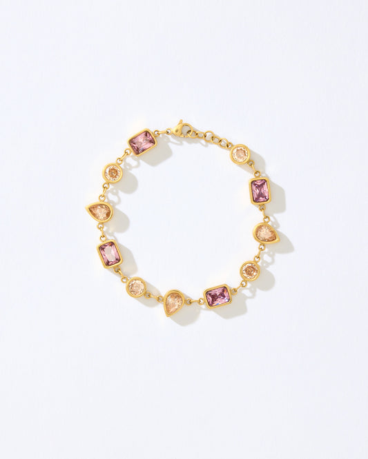 Gold bracelet with pink and orange gemstones on a white background