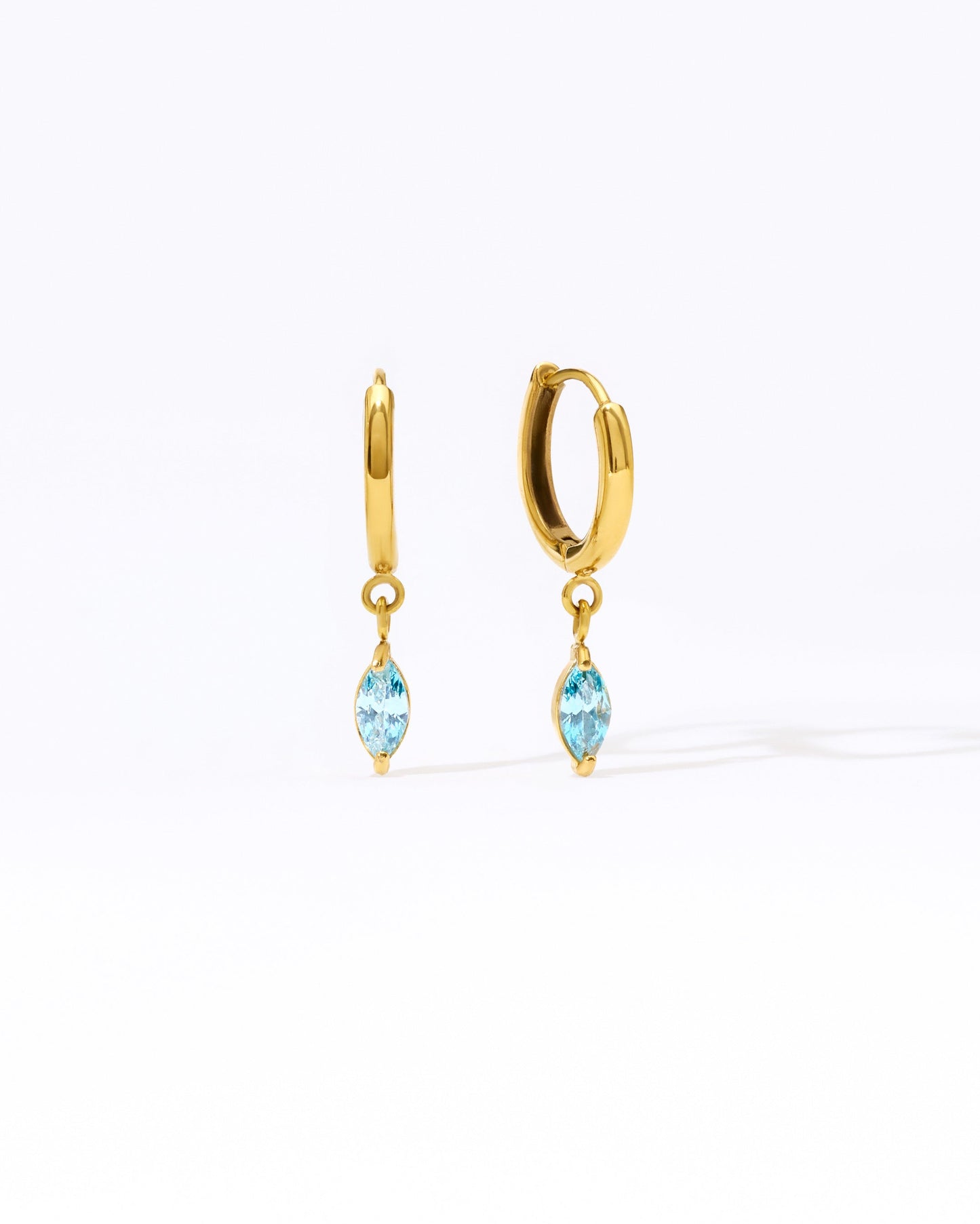 Gold hoop earrings with blue marquis gemstones on a white background